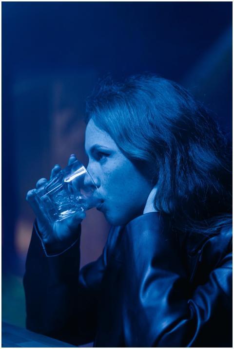 A woman in a black jacket enjoying a drink in a di
