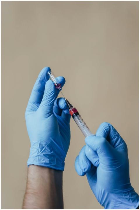 Close-up of gloved hands preparing a syringe with