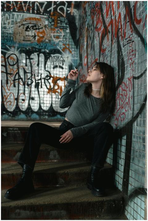 A woman sitting on graffiti-covered stairs, smokin