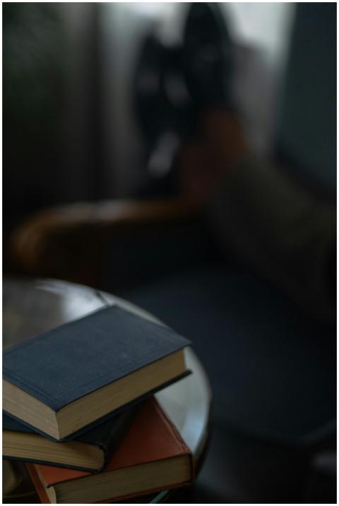 A stack of books on a wooden table in a cozy indoo