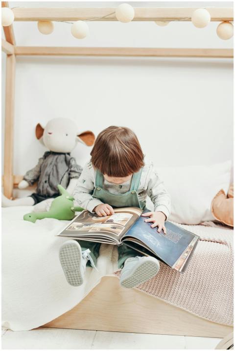 Adorable child reading a book in a cozy playroom,