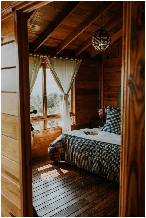 A rustic wooden bedroom with a cozy bed and natura