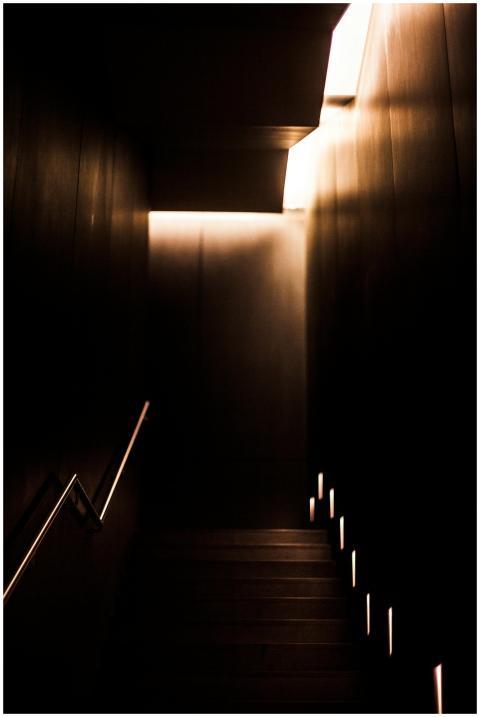 A dimly lit modern staircase with dramatic lightin