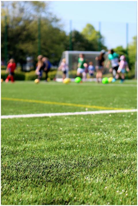 Blurred children playing soccer on a vibrant green