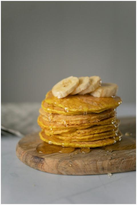 A stack of fresh banana pancakes drizzled with hon