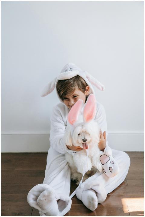 Boy dressed in bunny costume cuddling a dog with b