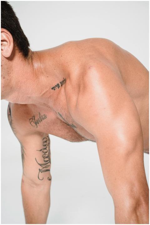 Shirtless tattooed man performing push-up exercise