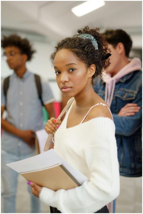 A young woman carries notebooks, embodying focus a