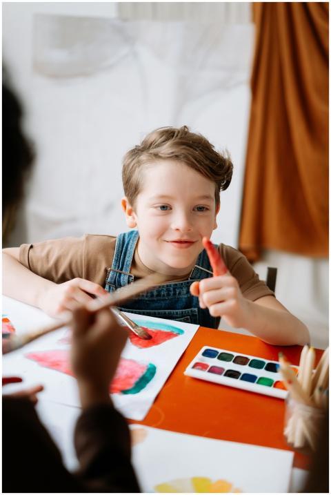A cheerful child paints with watercolors at a tabl