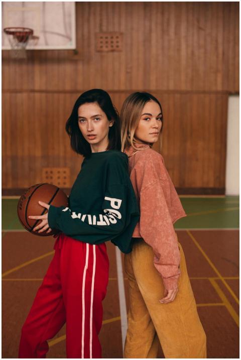 Two fashionable women posing with a basketball ind