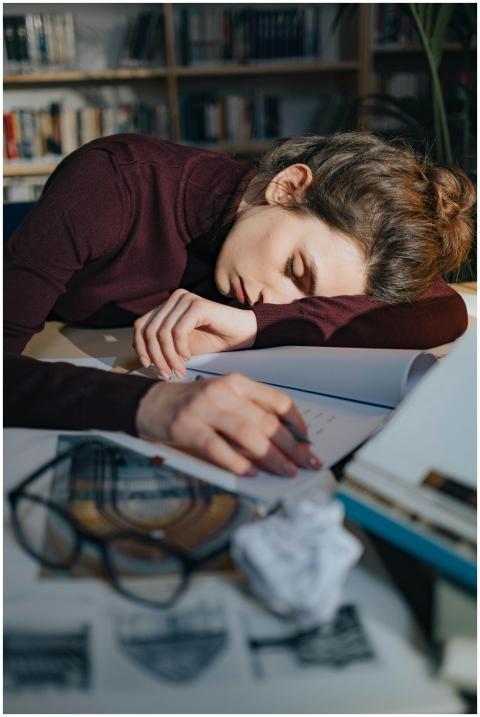 A tired woman sleeping on a desk surrounded by doc