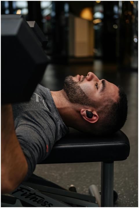 A focused man performing a bench press with dumbbe