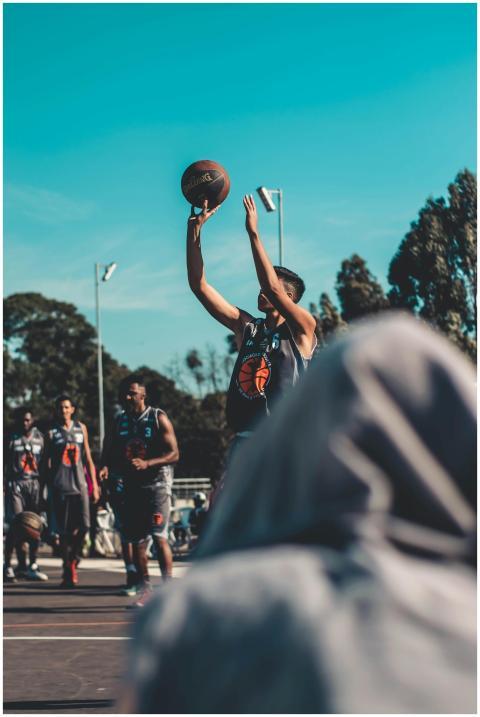 A group of men playing basketball outdoors on a su