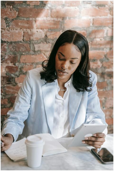 A focused woman in a blazer takes notes on a table