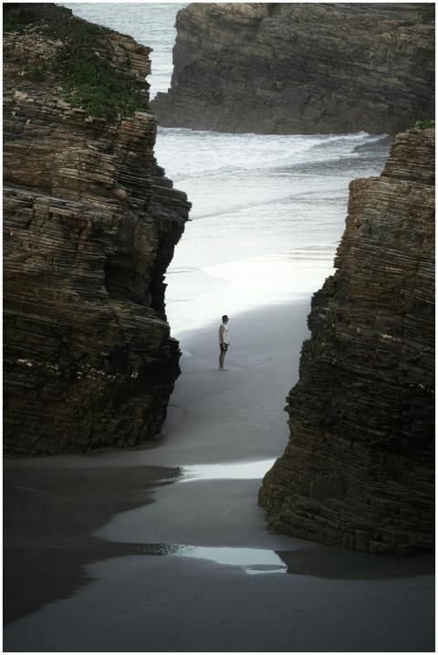 A lone traveler stands between towering cliffs at
