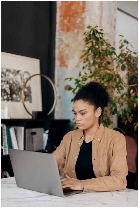 Young woman with curly hair working on a laptop in