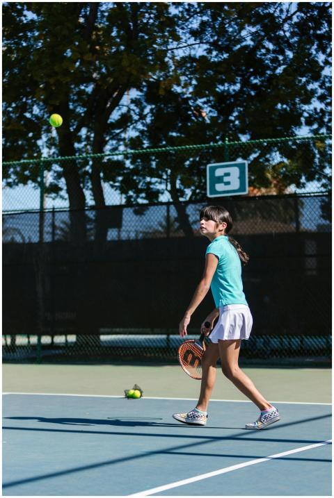 Girl practicing tennis on an outdoor court with a