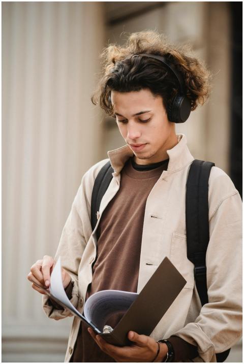 Concentrated male student looking through document