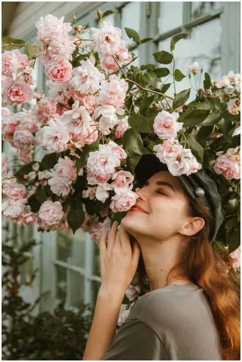 A woman delightfully poses with pink flowers, enjo