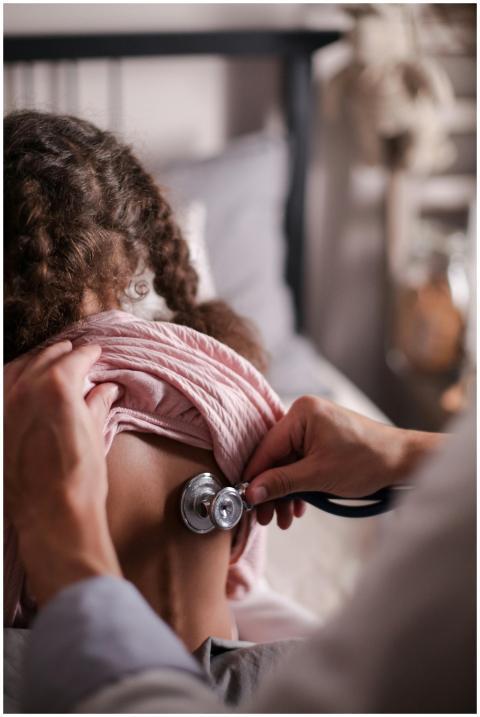 Doctor using stethoscope to check child's back dur