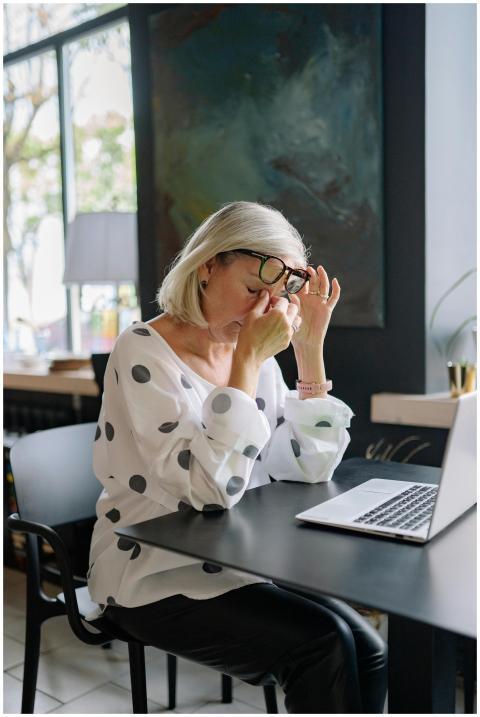 A tired businesswoman in a polka dot blouse sits a