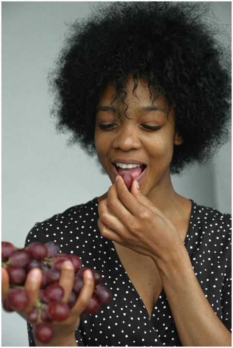 A beautiful woman enjoying a bunch of grapes. Polk