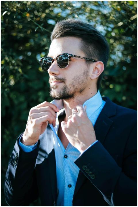 Fashionable man adjusting his suit and sunglasses