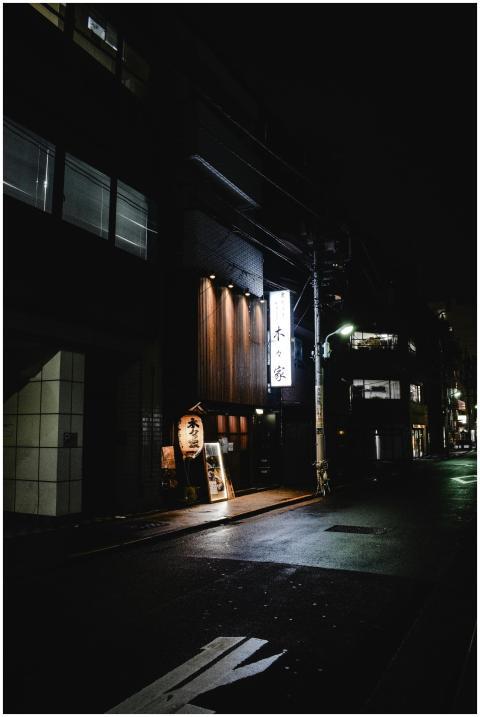 Dimly lit street scene at night featuring a restau