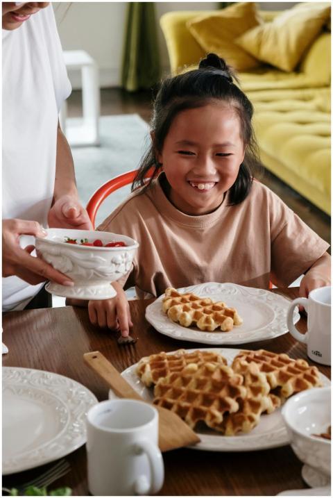 Smiling child enjoys waffles during a cheerful fam