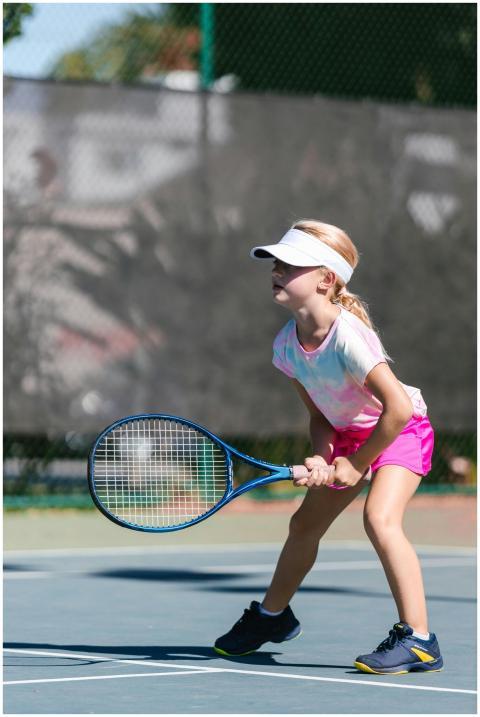 Young girl practicing tennis on an outdoor court i