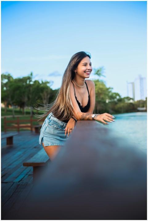A young woman leans on a railing, smiling against