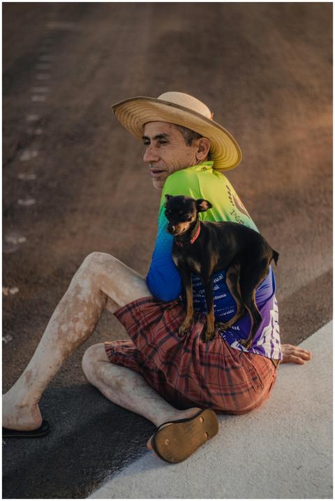 A man in a straw hat sits on a rural Brazilian roa