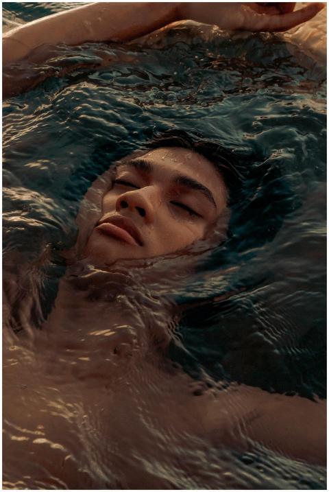 A peaceful adult submerged in water, eyes closed,