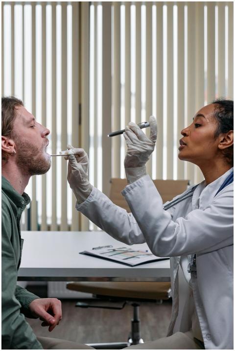 A doctor examines a patient by checking his throat