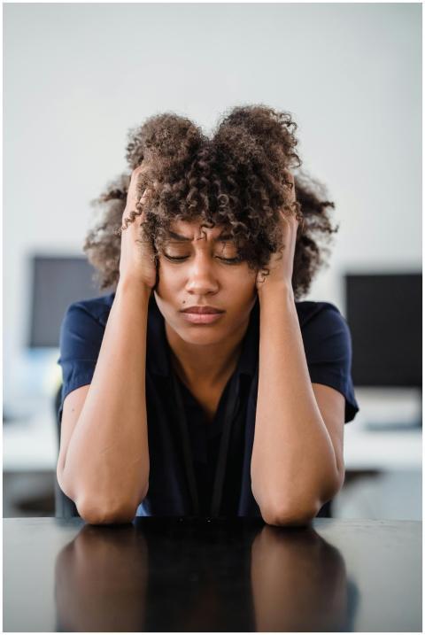 Woman in office setting expresses stress, seated a