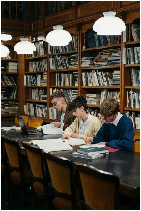 Students engaged in study at a library table surro