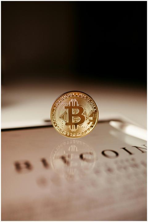 A close-up of a golden Bitcoin coin standing on a