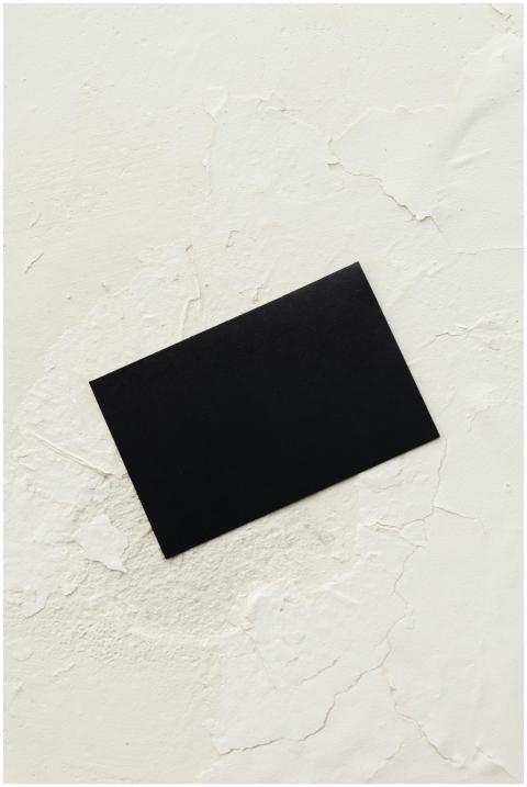 A black business card placed on a cracked white te