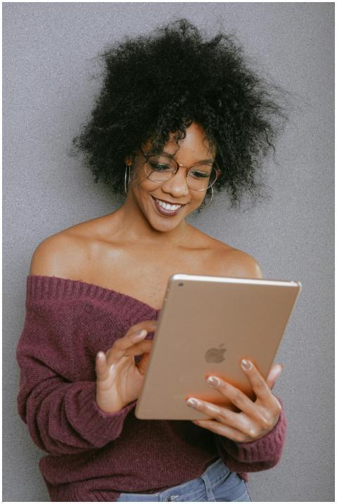 A young woman with curly hair smiling while using