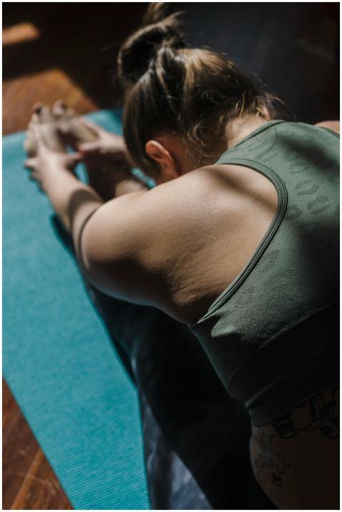A woman stretches in a yoga pose on a blue mat ind