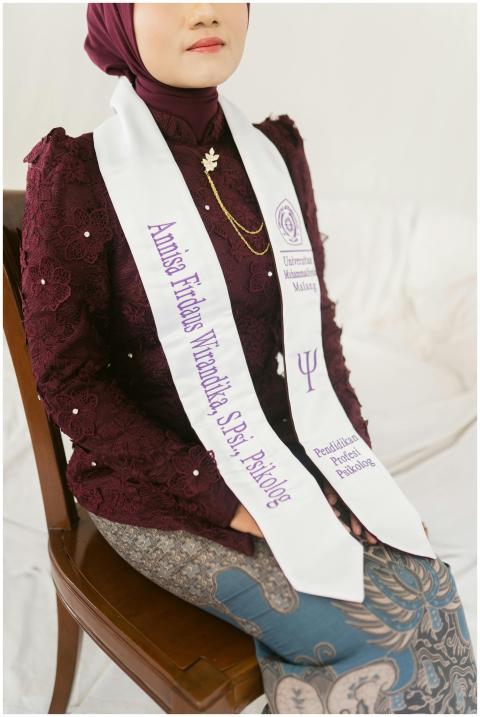 Woman wearing maroon academic robe and white sash