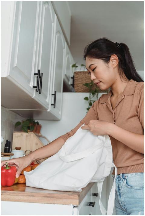 A young woman unpacks groceries on a kitchen count