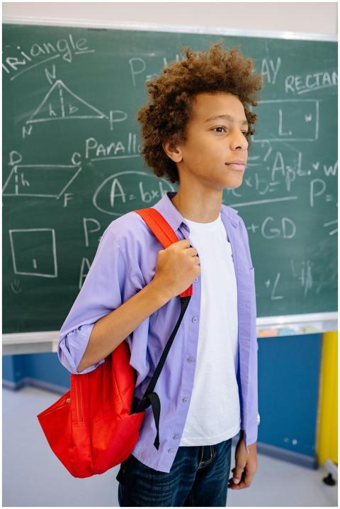 Teenage student with red backpack standing in fron