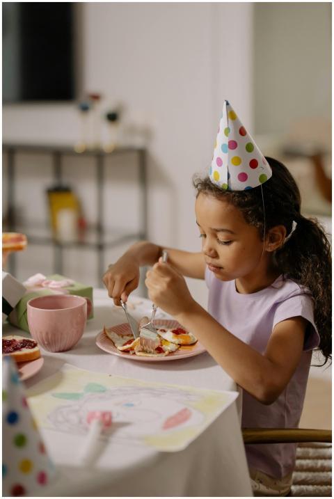 Girl at birthday party eating cake, wearing a fest