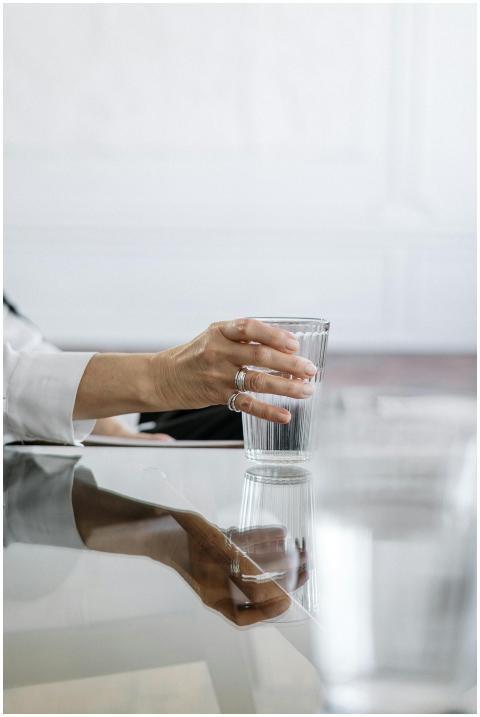 Close-up of a hand with rings holding a glass on a
