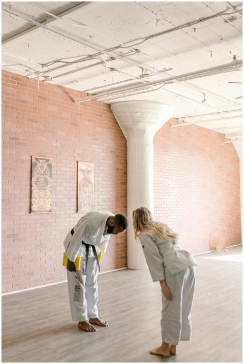 Two martial artists practice bowing in a bright do