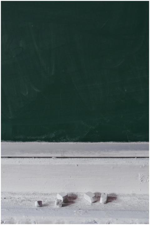 A dusty blackboard with chalk pieces, ideal for ed