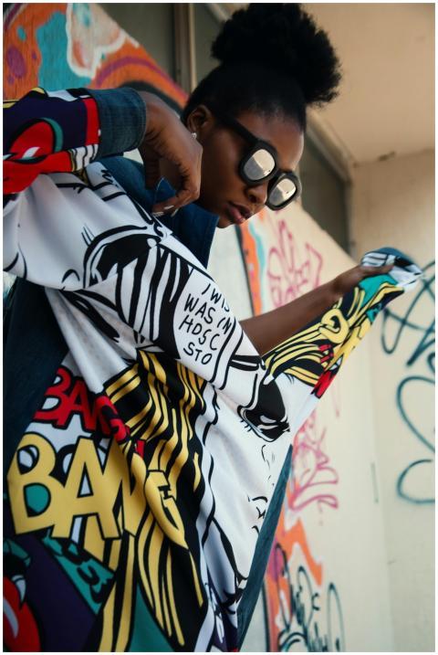 Fashionable woman in colorful outfit posing agains