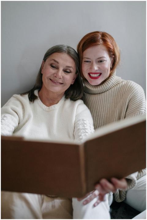 Elderly woman and adult daughter reading a book to