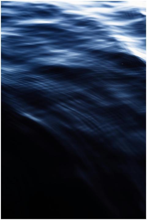 Close-up of serene dark blue water waves creating